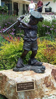 Statute of a little boy win Dad's golf shoes and club titled, "Just Like Dad's"